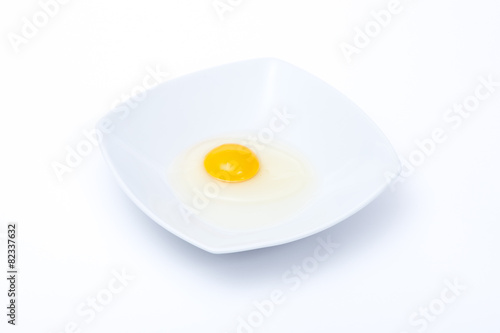 uovo crudo in un piatto bianco su sfondo bianco