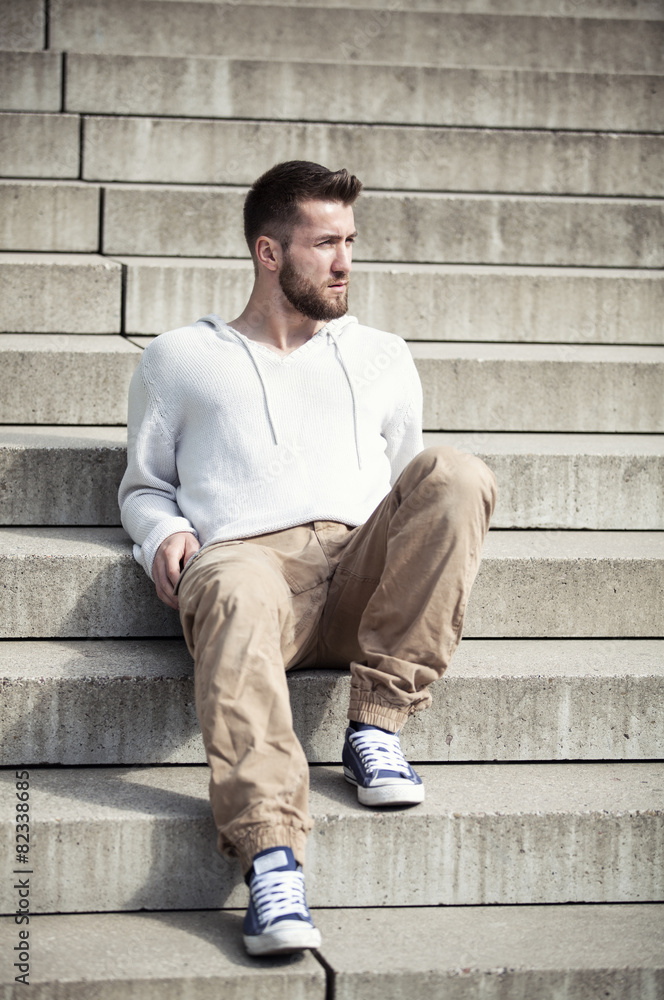 Attraktiver Mann mit Bart sitzt auf einer Treppe