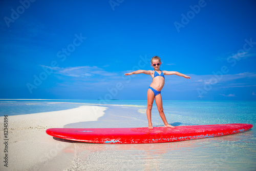 Photography Little adorable girl practice surfing position at beach