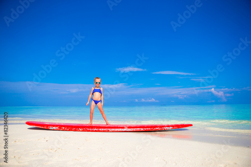Little adorable girl practice surfing position at beach