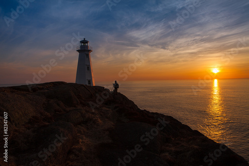 Photographer at Lighthouse at Ocean Sunrise Orange Horizon Blue Skies