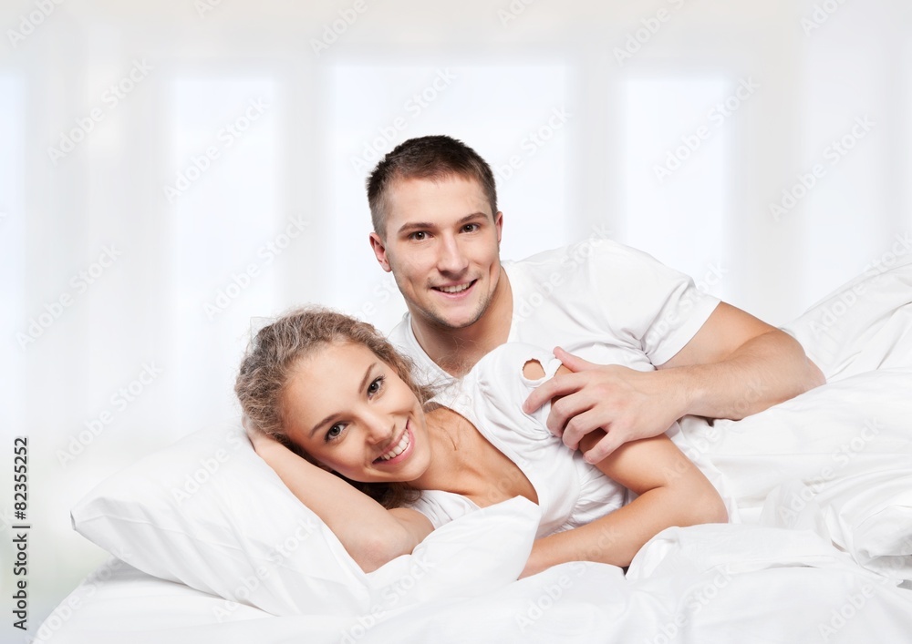 Adult. Young adult heterosexual couple lying on bed in bedroom Adult. Young adult heterosexual couple lying on bed in bedroom