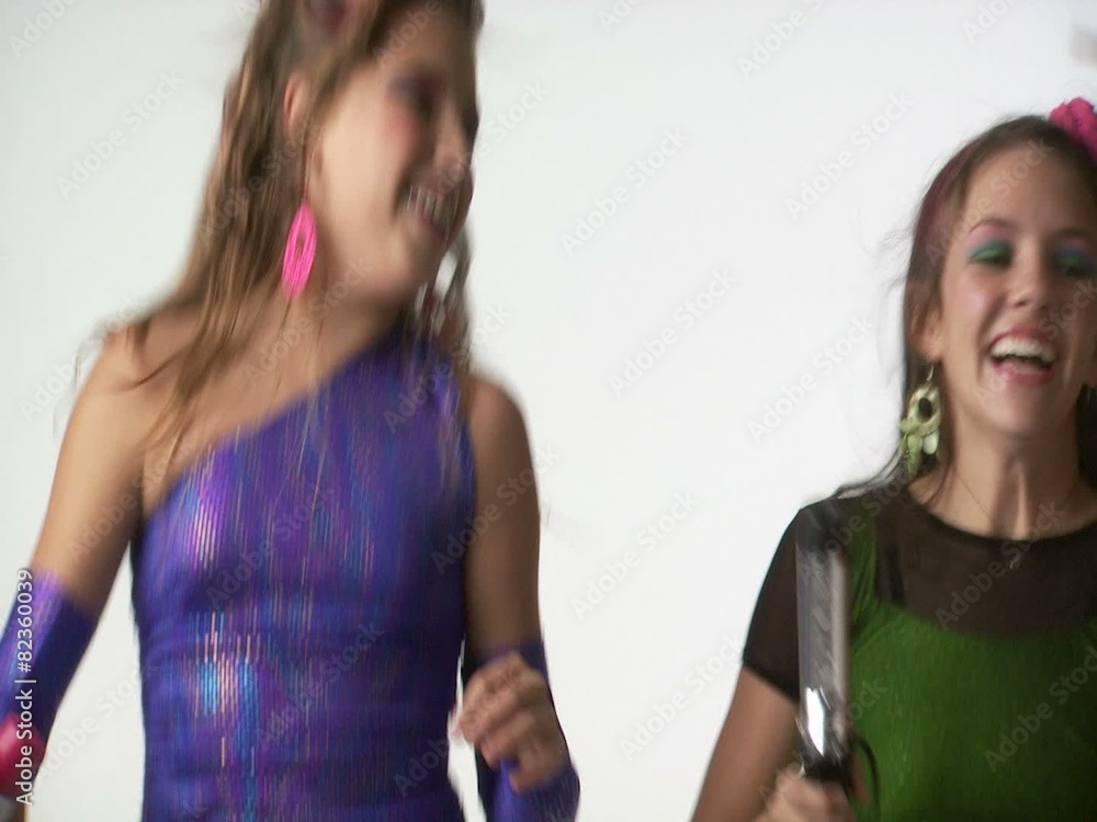 Teenage girls dancing and singing into curling iron and hairbrush Teenage girls dancing and singing into curling iron and hairbrush