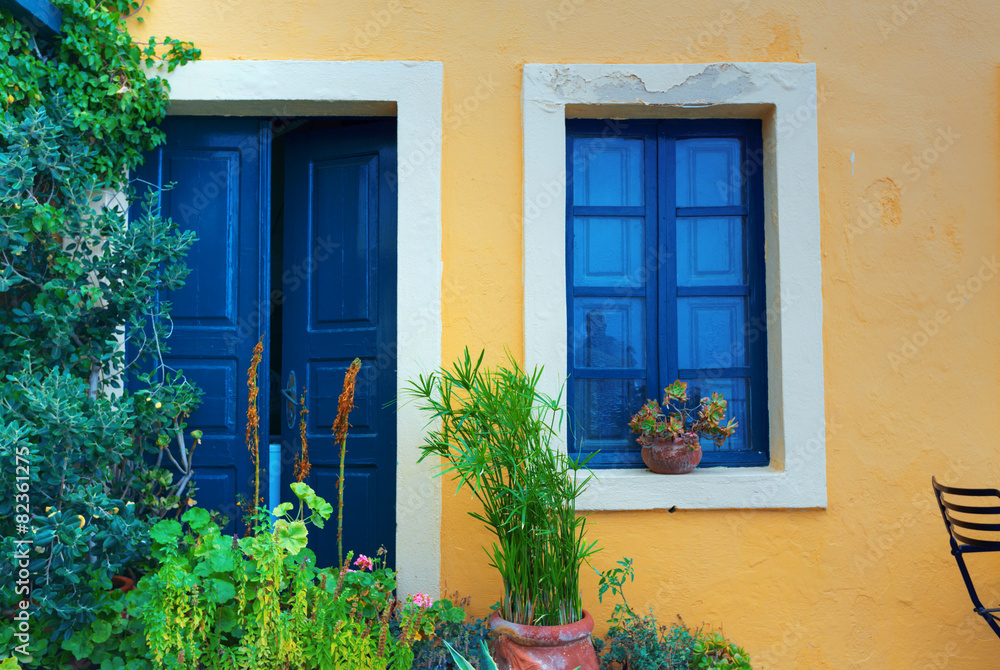 Old house yellow wall with blue door and window. Greece Santorin