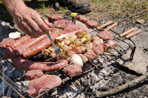 Beef steaks and sausages cooking in open flame on barbecue grill