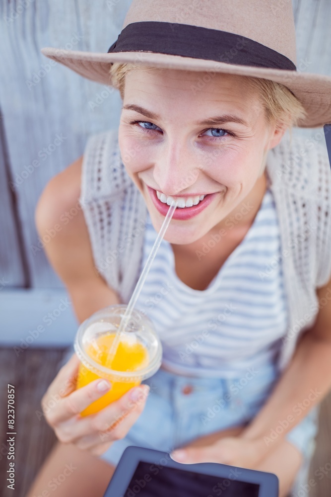 Pretty blonde woman using her tablet and holding orange juice Pretty blonde woman using her tablet and holding orange juice