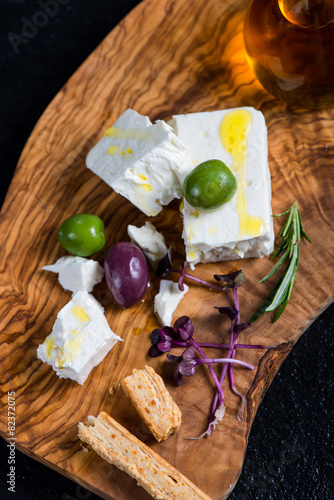 Feta cheese on wooden board with olives and oil