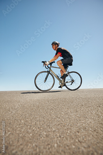 Male cyclist riding bicycle on flat road