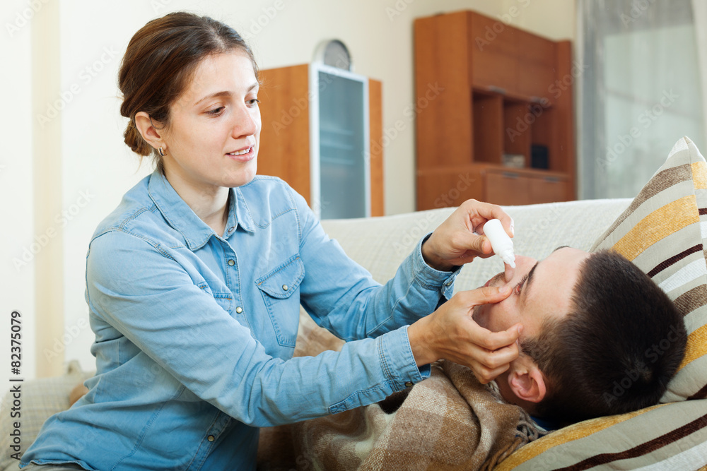 Fototapeta premium woman dripping eye drops to man