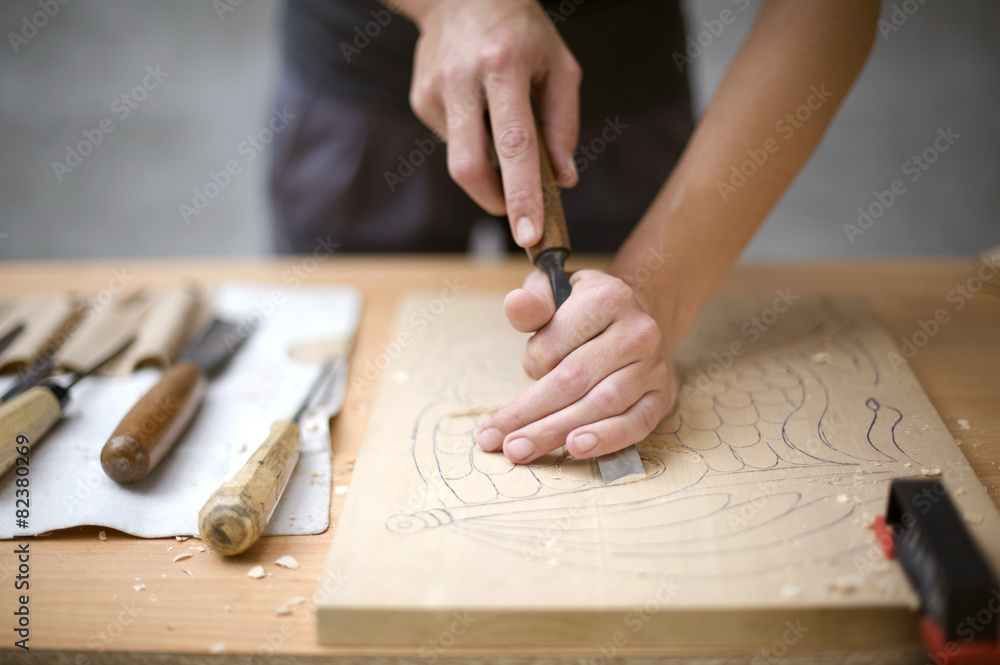 Artist carves a wooden plate with a chisel Artist carves a wooden plate with a chisel