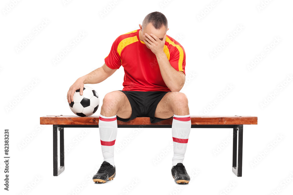 Worried football player sitting on a bench