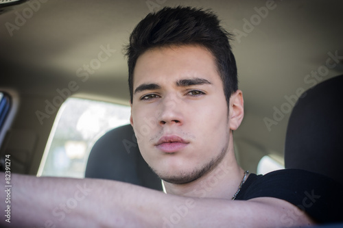 Serious young man or teenager driving car