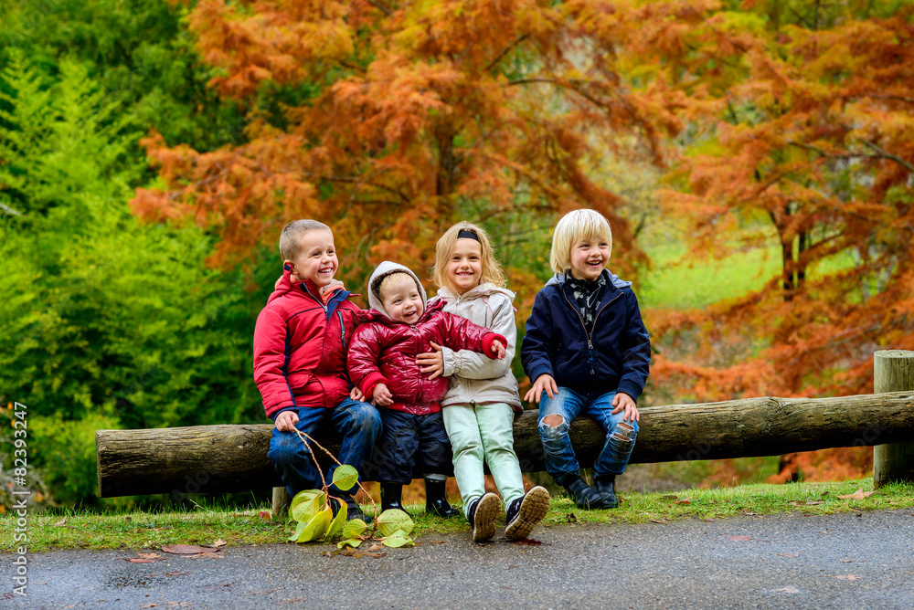 Three boys and girl sitting together in autumn park Three boys and girl sitting together in autumn park