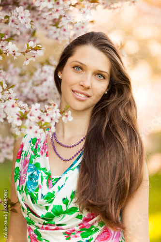 Beautiful brunette woman in blooming orchard