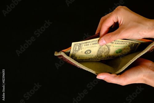 Empty wallet with one dollar on black background photo