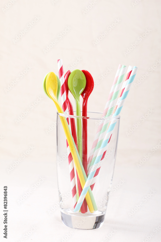 colorful spoon and stripped straw in clear glass