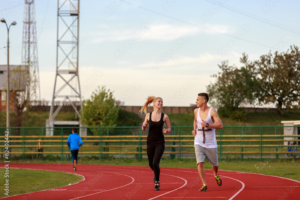 Fototapeta premium An attractive man and woman jogging on the track