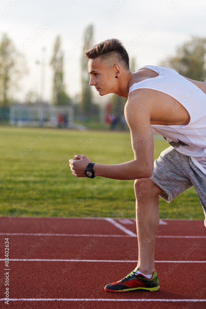 Obraz premium Young athlete running at the running track holding a stopwatch