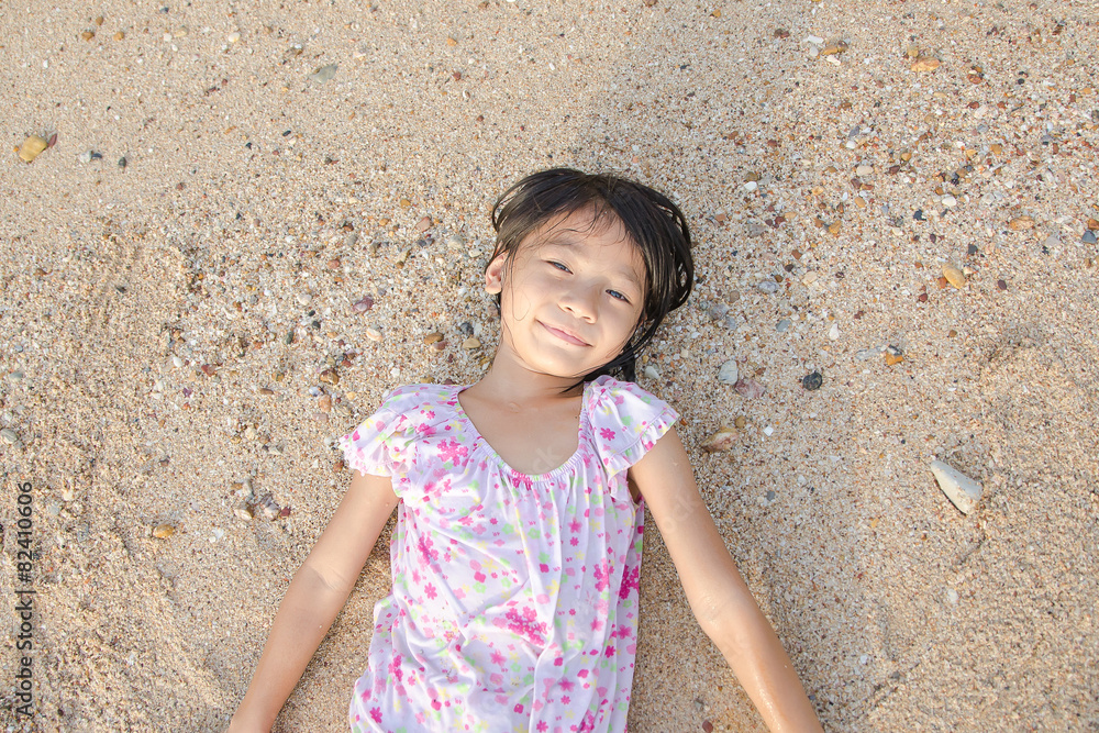 Asian smiling cute little girl lying on the beach sand. Thai chi Asian smiling cute little girl lying on the beach sand. Thai chi