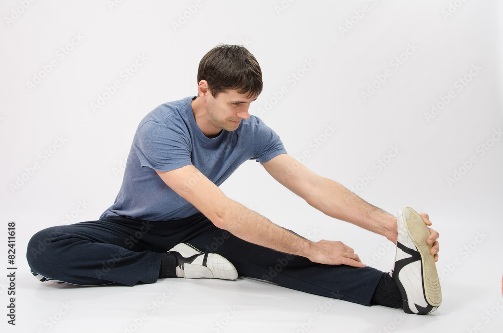 Fototapeta premium The young man stretches muscles of left leg
