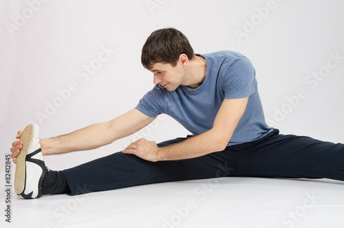 Athlete in training stretches the muscles of right leg