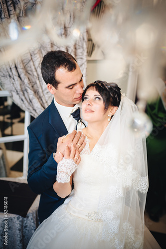 Charming bride with groom embraces and kisses on their wedding