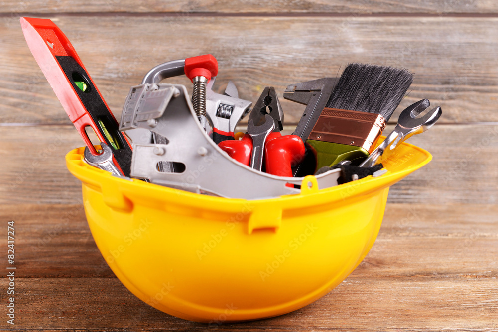 Construction tools in helmet on wooden background