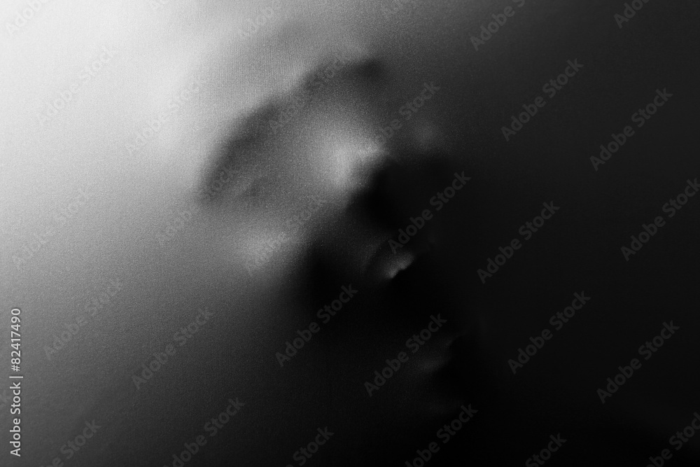 Screaming human face pressing through fabric as horror background Screaming human face pressing through fabric as horror background