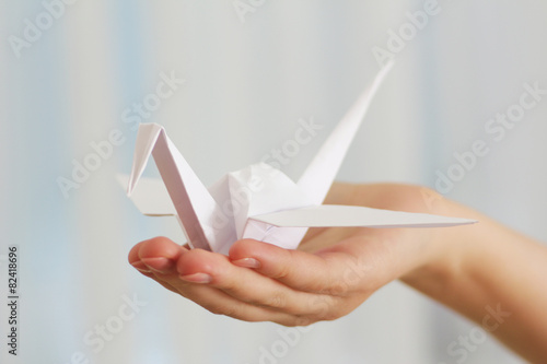 Female hand with paper crane on blurred background