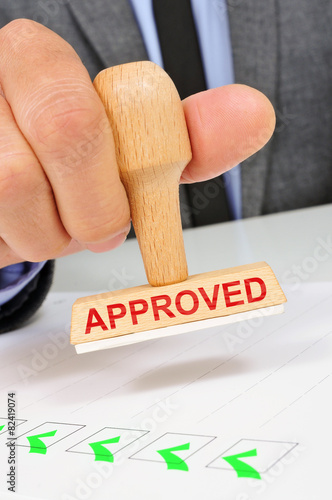 man with a rubber stamp with the word approved