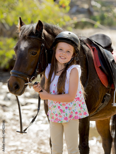 happy child girl with pony horse as young jockey in Summer