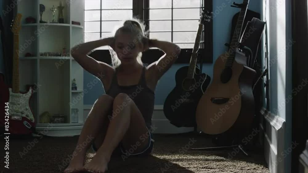 Medium shot of teenage girl doing sit-ups in bedroom / Sandy, Utah, United States Medium shot of teenage girl doing sit-ups in bedroom / Sandy, Utah, United States