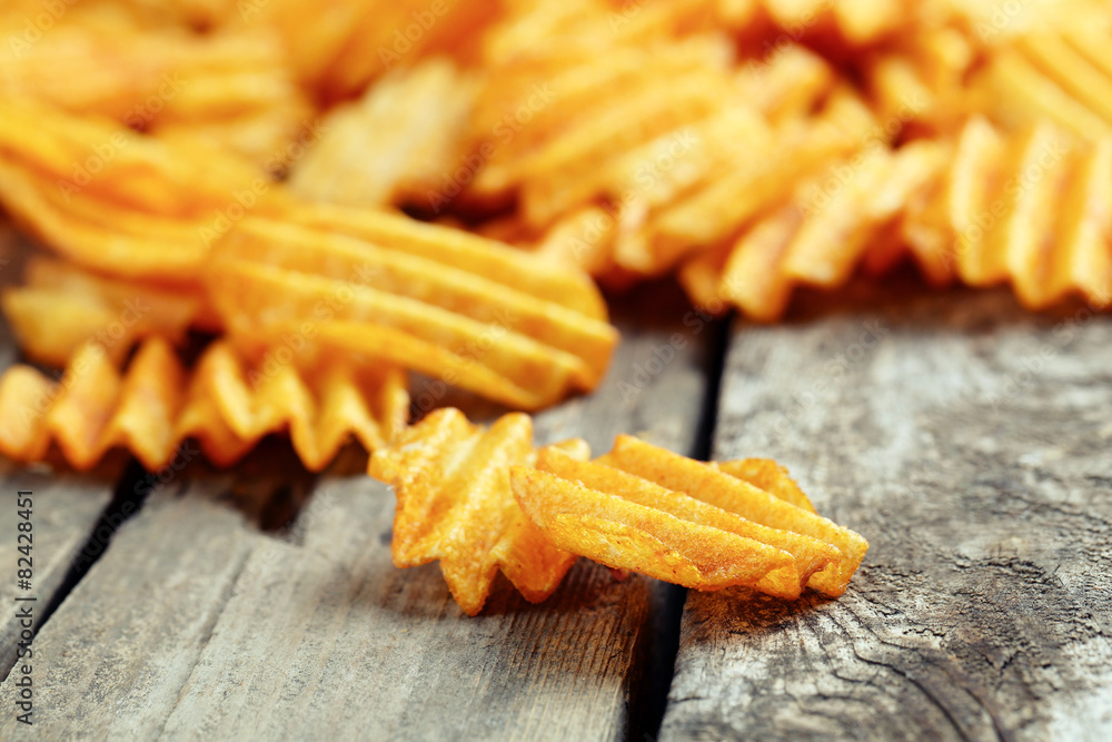 Delicious potato chips on wooden table close-up Delicious potato chips on wooden table close-up