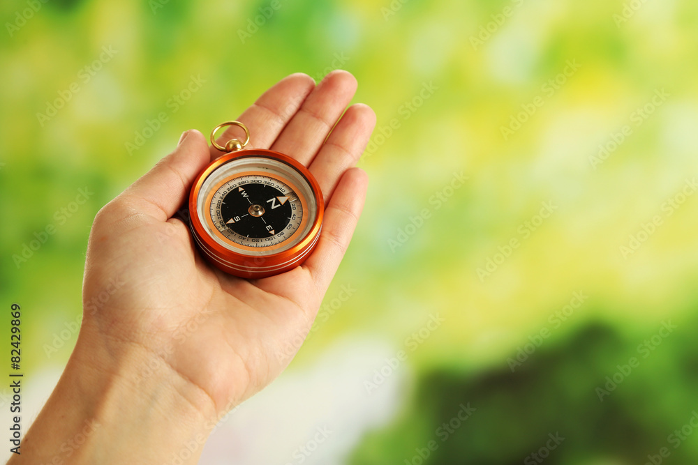 Female hand with compass on bright blurred background Female hand with compass on bright blurred background