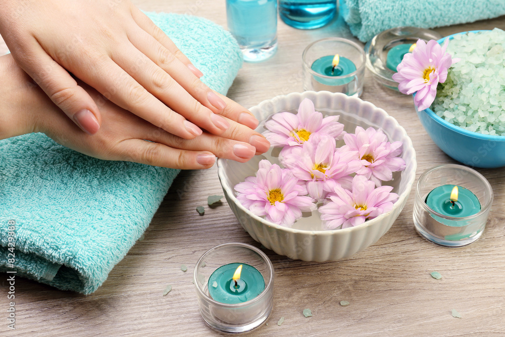 Female hands with bowl of aroma spa water on wooden table, closeup Female hands with bowl of aroma spa water on wooden table, closeup
