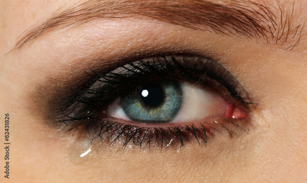 Obraz premium Eye of young woman with tear drop close up