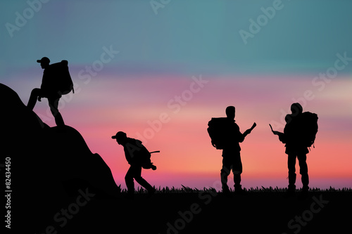 Hiker with backpack standing on a rock and enjoying sunset