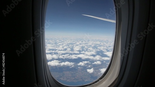 Clouds seen through the window of jet airplane. Airplane flies above the weather