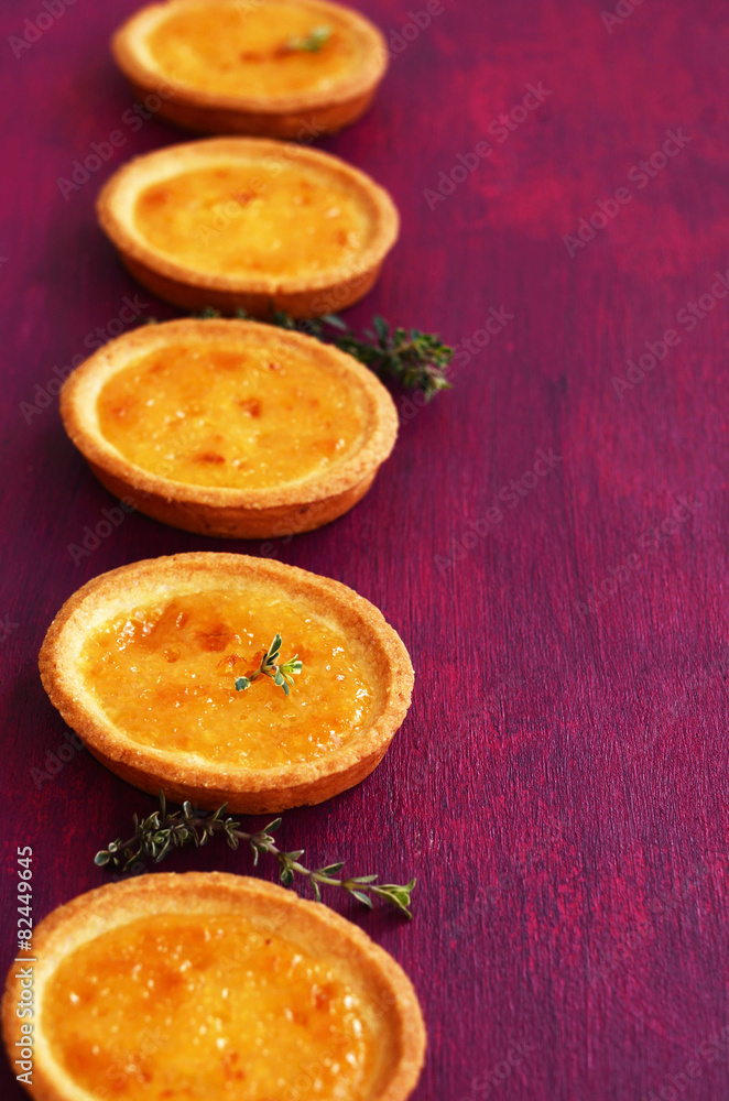 Lemon tartlets with thyme on fuchsia color background Lemon tartlets with thyme on fuchsia color background