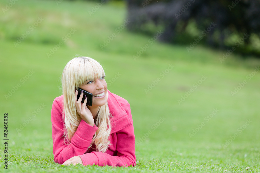 Junge Frau telefoniert liegend auf der Wiese Junge Frau telefoniert liegend auf der Wiese