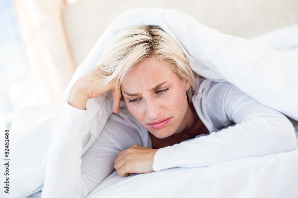 Fototapeta premium Sad blonde woman lying on the bed