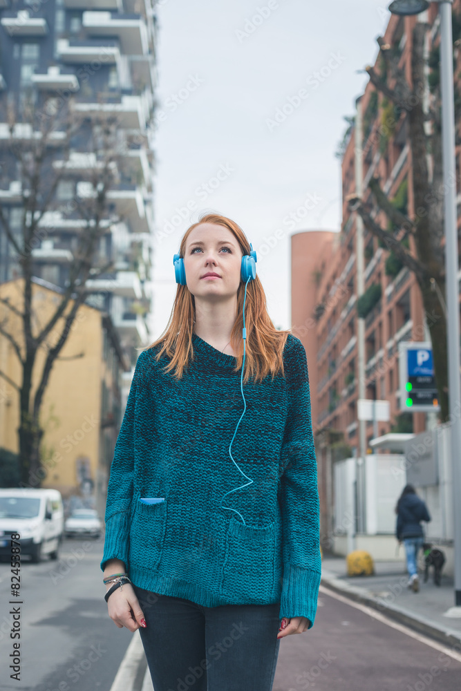 Fototapeta premium Beautiful girl listening to music in the city streets