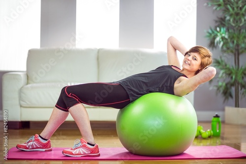 Fit woman doing sit ups on exercise ball