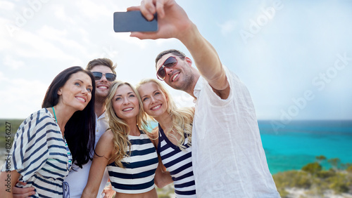 friends on beach taking selfie with smartphone