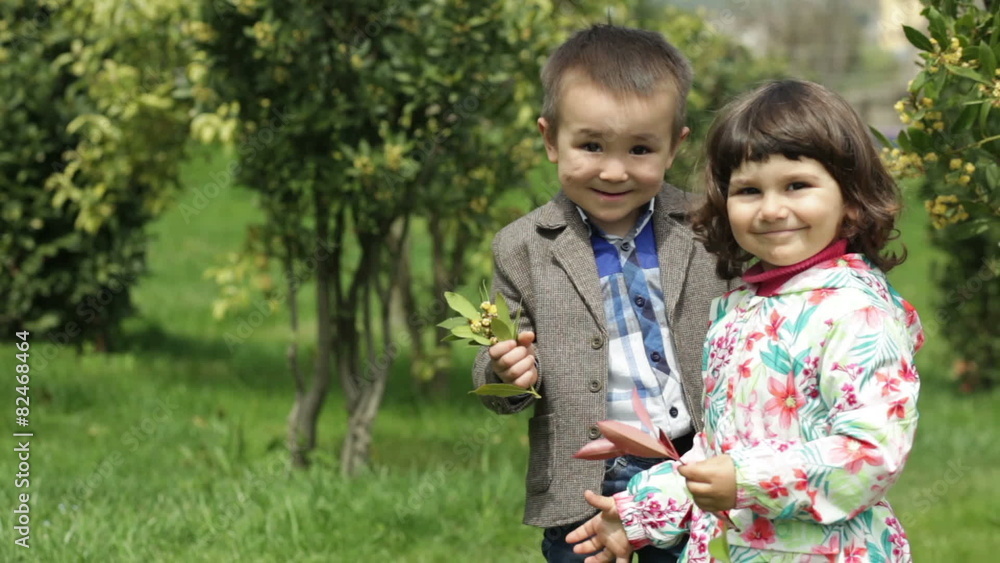boy sniffing sprig of tree and kissing girl cheek boy sniffing sprig of tree and kissing girl cheek