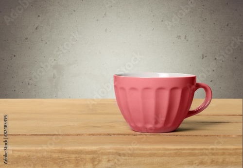Abstract. Red cup with dots on wooden table over grunge