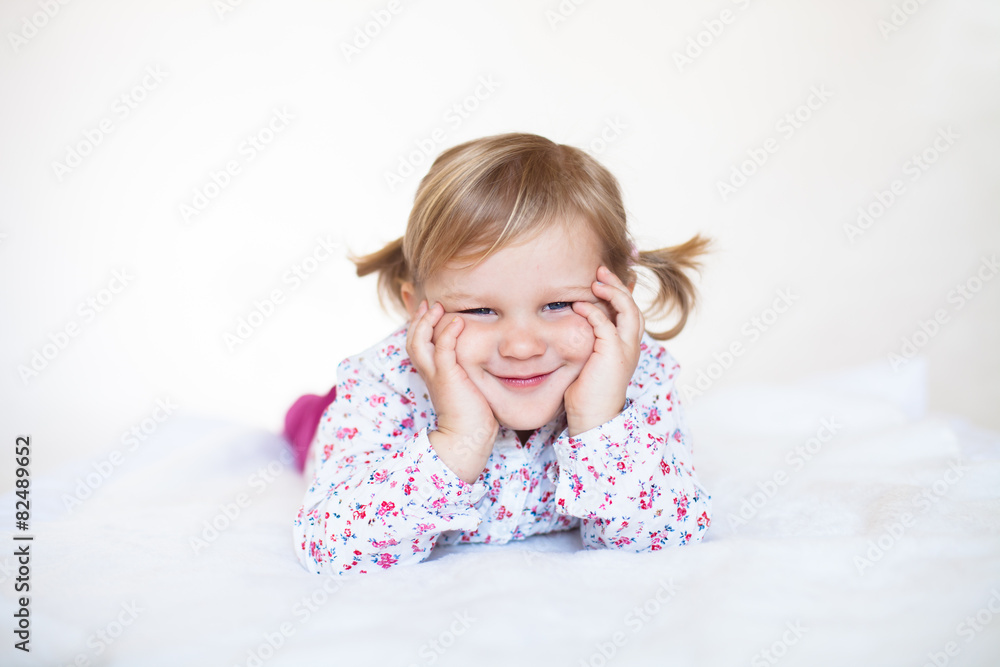 Little cute smiling baby girl lying on the white blanket Little cute smiling baby girl lying on the white blanket