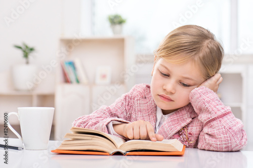 Little cute girl sadly reading book