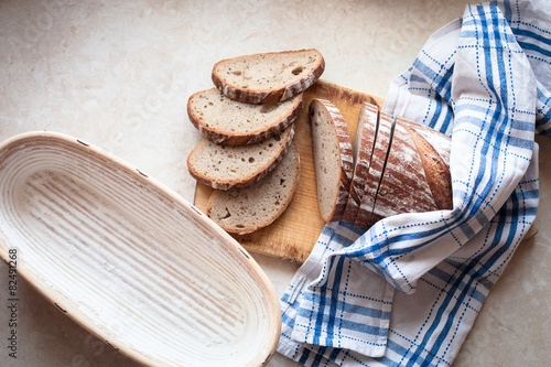 Sliced bread on a woody cutting board on desk with bascet and na