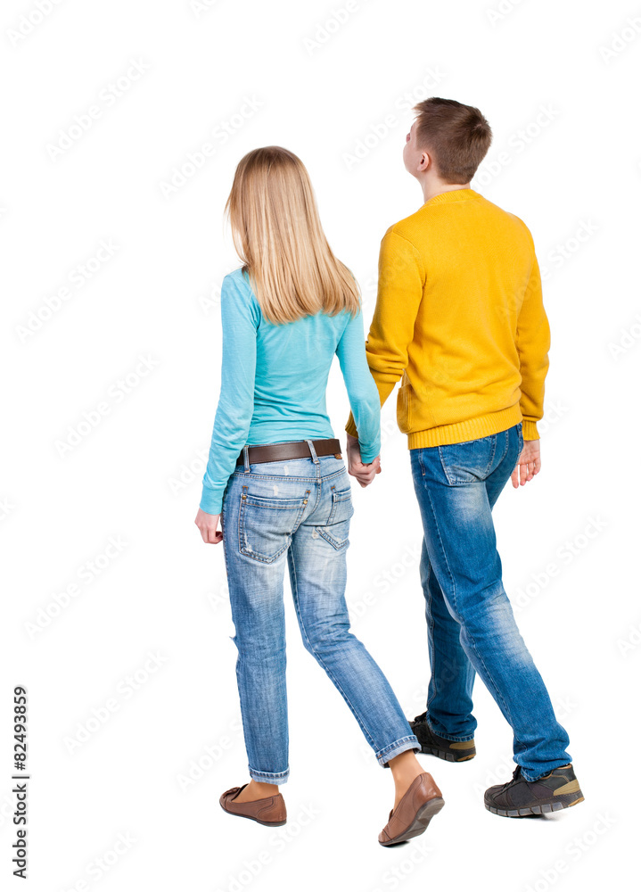 Back view going couple. walking friendly girl and guy holding h